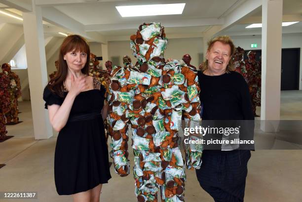 June 2020, North Rhine-Westphalia, Duesseldorf: Action artist HA Schult and his wife Anna Zlotovskaya stand next to one of the artist's "Trash...