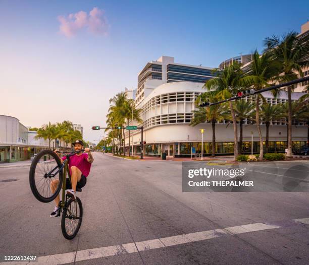 bmx style wheel up in an empty miami beach street - wheelie stock pictures, royalty-free photos & images