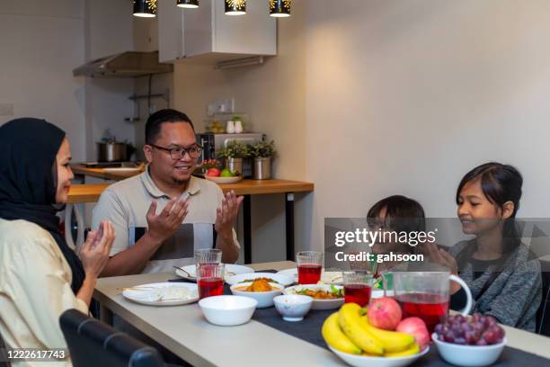 muslim family praying together before breaking fast during the month of ramadan - fasting activity stock pictures, royalty-free photos & images