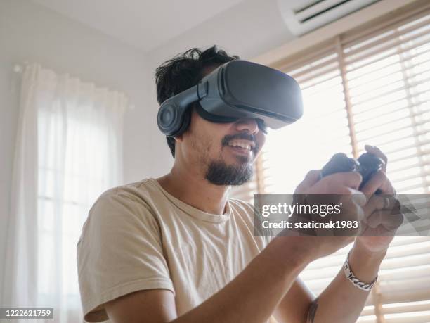 asian man playing video game with vr in the bedroom at home. - esports stock pictures, royalty-free photos & images
