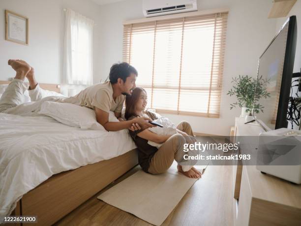 alegre familia asiática relajarse en casa viendo la televisión en casa. - lovers 2020 film fotografías e imágenes de stock