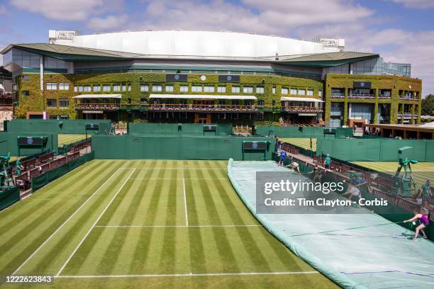 June 30: Ground staff remove the covers on an outside court with the back drop of Centre Court during the Wimbledon Lawn Tennis Championships at the...