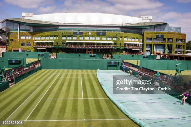 June 30: Ground staff remove the covers on an outside court with the back drop of Centre Court during the Wimbledon Lawn Tennis Championships at the...
