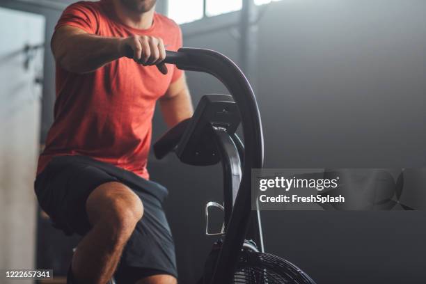 unrecognizable  man doing exercise on a gym stationary bike, gym concept - red tops stock pictures, royalty-free photos & images