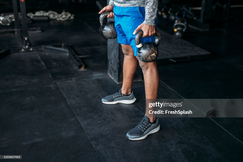 Anonymous Sportsman Lifting Kettlebells at the Gym