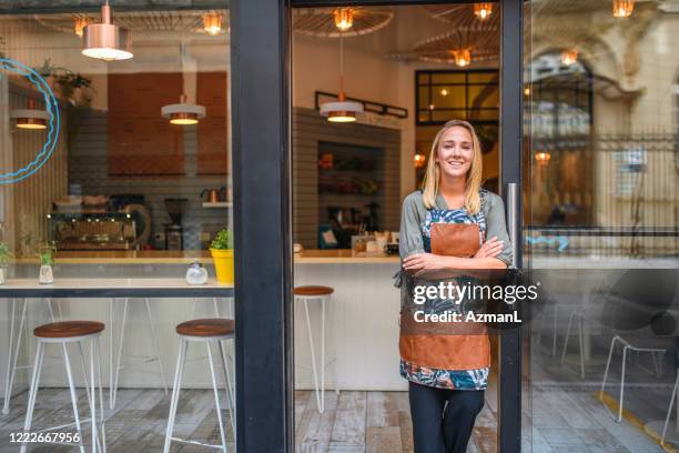 female small business owner standing at open door - cafe owner fotografías e imágenes de stock