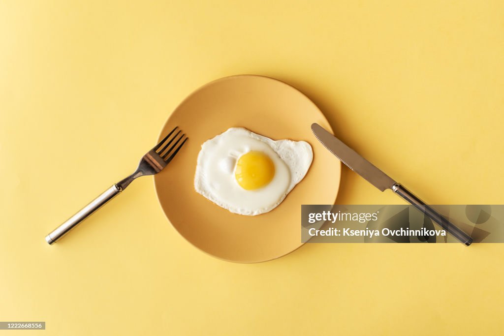 Fried egg on yellow background, top view