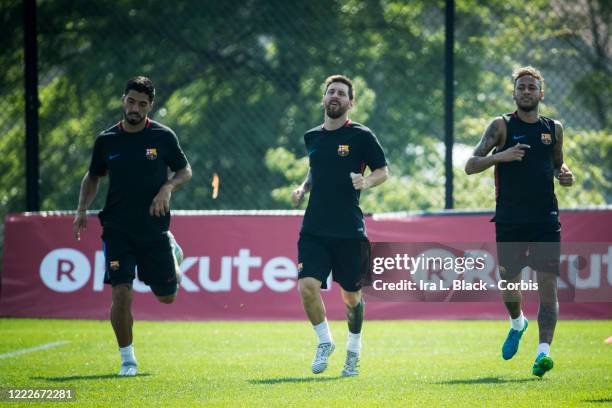 Lionel Messi of Barcelona and Neymar of Barcelona and Luis Suarez of Barcelona run next to each other on the field to warm up with the Raktuten logo...