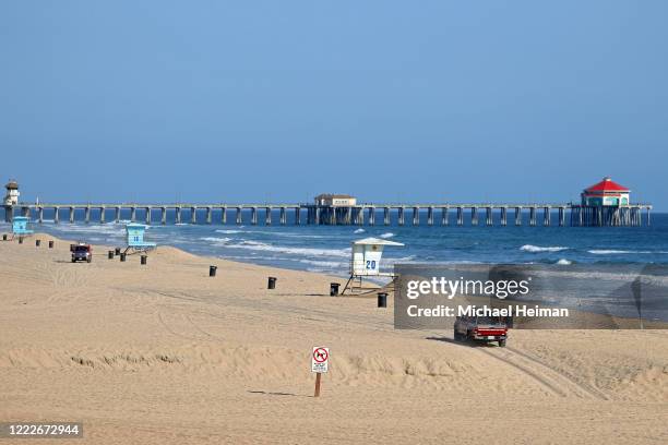 Lifeguards patrol an empty beach in front of the Huntington Beach Pier on May 3, 2020 in Huntington Beach, California. California Gov. Gavin Newsom...