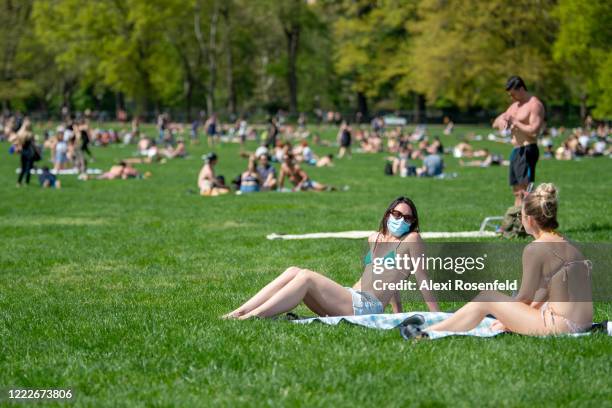 Woman wearing a mask sits in Sheep Meadow, Central Park as temperatures rise amid the coronavirus pandemic on May 3, 2020 in New York City. COVID-19...