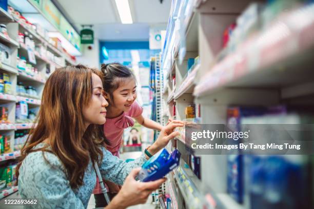 mom & little daughter shopping in a drugstore joyfully - asian family shopping foto e immagini stock