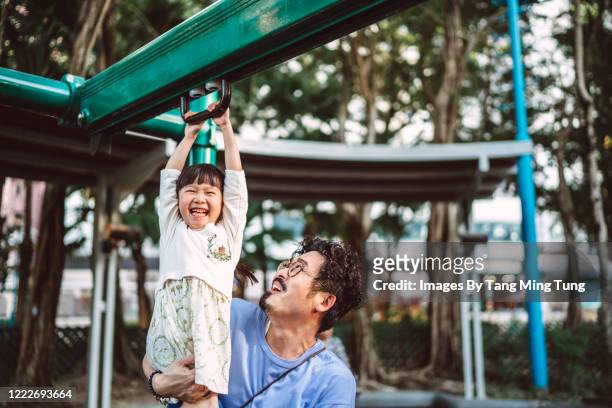 young asian dad playing with her little daughter with climbing rings at playground joyfully - monkey bars stock pictures, royalty-free photos & images