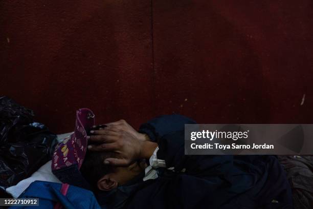 Juan Rodríguez Molina rubs his eyes as he lies on a makeshift bed on a sidewalk in the Buenavista neighborhood on June 20, 2020 in Mexico City,...