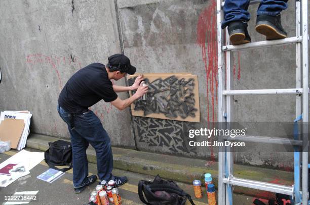 Stencil artists paint the walls of a subway at a giant new exhibition space in Leake Street Arches created by famed graffiti artist Banksy on May 3,...