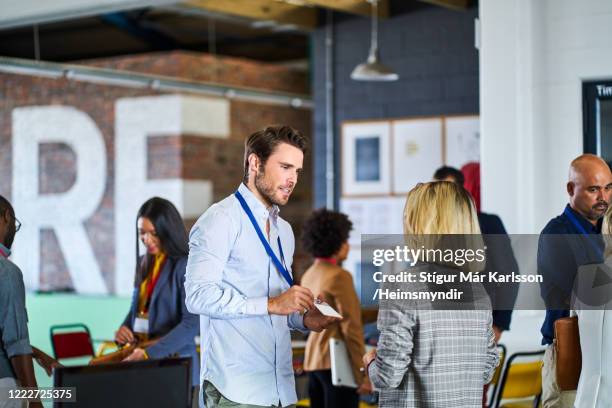 businessman showing lanyard to coworker in seminar - lanyard stock pictures, royalty-free photos & images