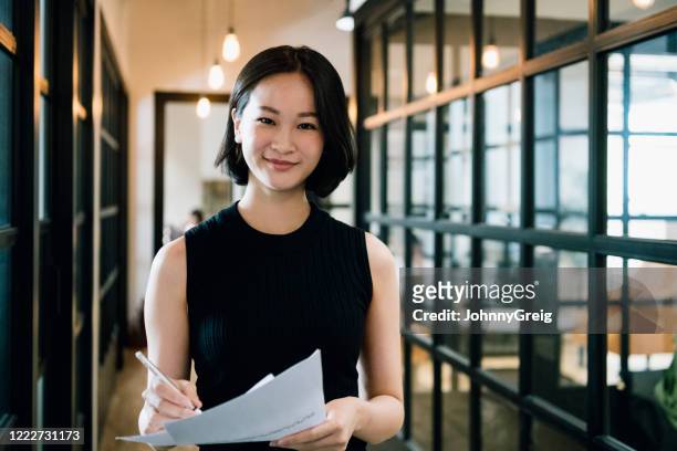 fröhliche geschäftsfrau in ihren 30er jahren mit papierkram - asia stock-fotos und bilder