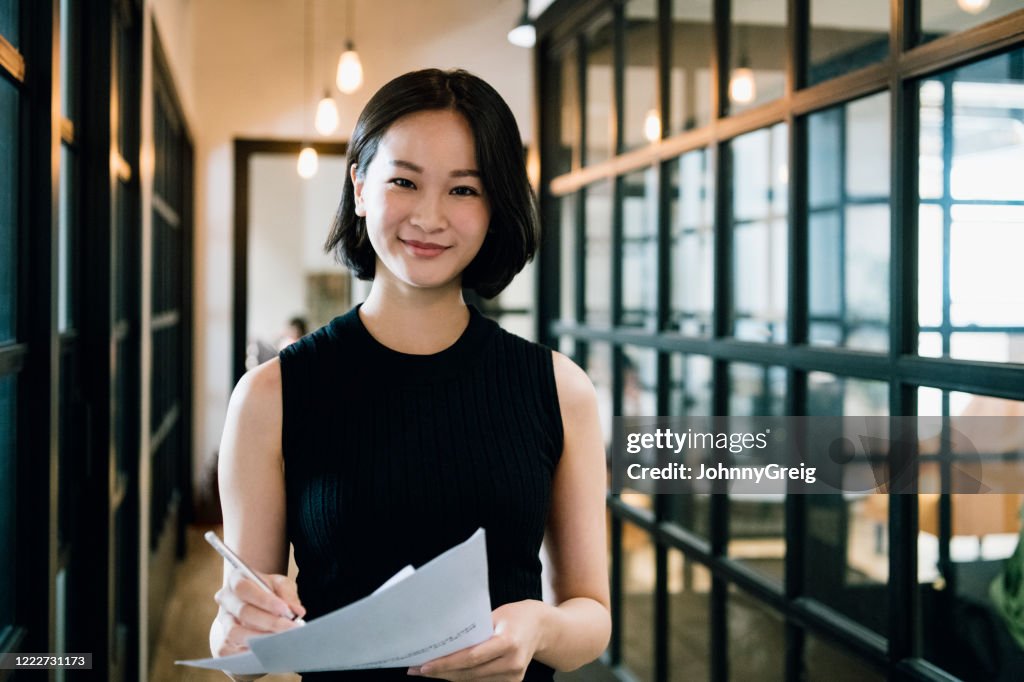 Cheerful businesswoman in her 30s with paperwork