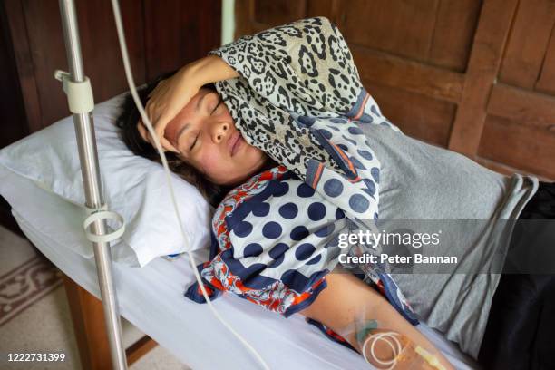 asian woman being treated at home for virus symptoms - dengue stock pictures, royalty-free photos & images