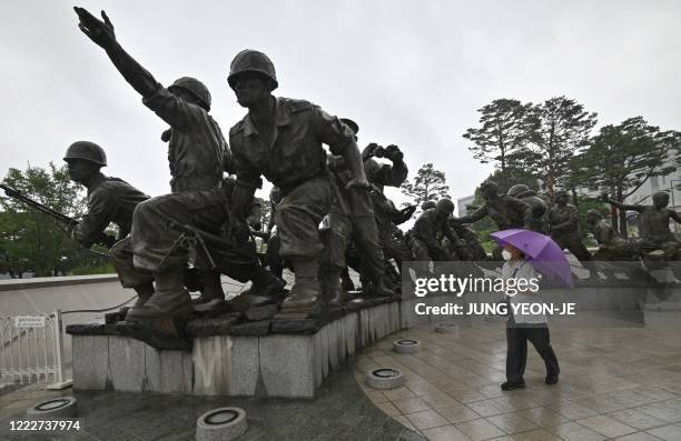 Man walks past bronze statues displayed at the Korean War Memorial in Seoul on June 25, 2020. - South Korea and the United States on June 25...