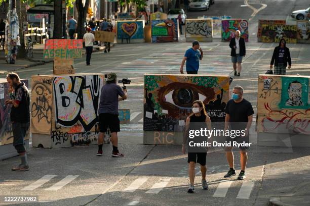 People walk by barricades in the area known as the Capitol Hill Organized Protest on June 24, 2020 in Seattle, Washington. On Monday, Seattle Mayor...