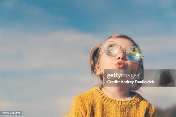 petite fille dans les verres de kaléidoscope drôle regarde vers le ciel avec la bouche ouverte et la curiosité. - kaléidoscope photos et images de collection