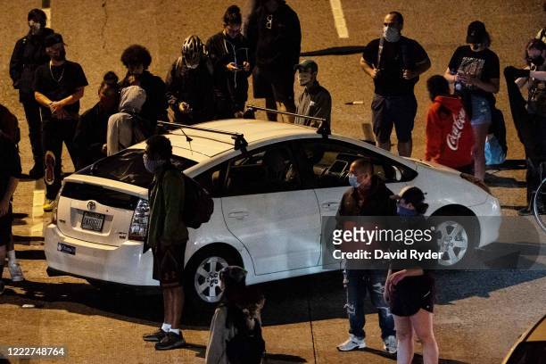 Protesters surround a car as they block Interstate 5 after marching from the area known as the Capitol Hill Organized Protest on June 24, 2020 in...