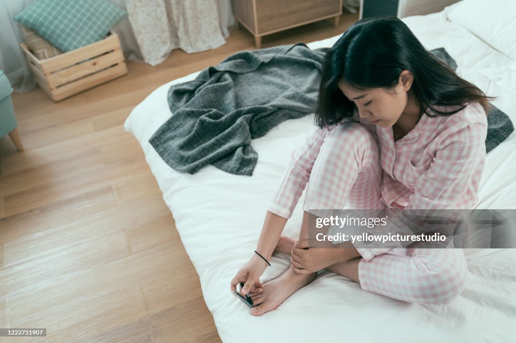 Senhora de pijama rosa usando cortador de unhas