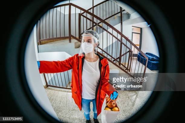 woman delivering groceries during lockdown - looking through hole stock pictures, royalty-free photos & images