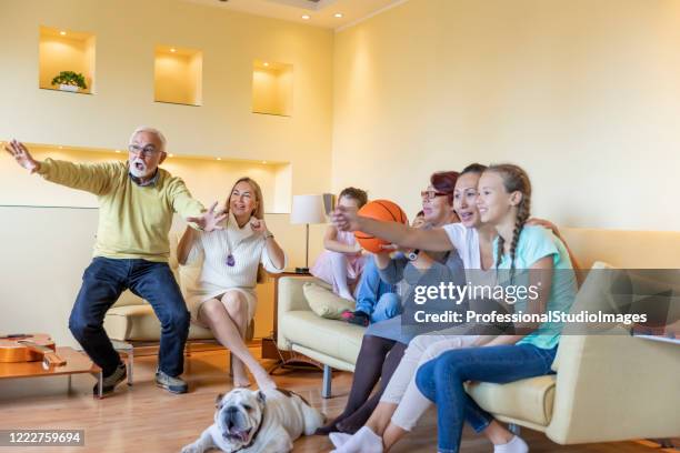 happy family members are spending wonderful time together while watching a  basketball game. - family tv pet stock pictures, royalty-free photos & images