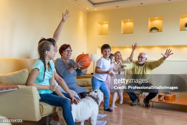 happy family members are spending wonderful time together while watching a  basketball game. - family tv pet stock pictures, royalty-free photos & images