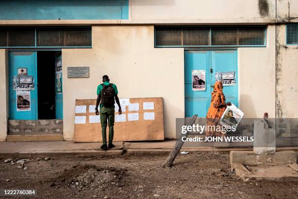 High School student at the Lycee Blaise Diagne checks a list to see in which classroom he will be on his first day back at school whilst a teacher...