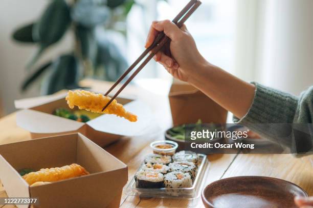 young woman eating takeaway asian meal at home - sushi chopsticks stock pictures, royalty-free photos & images