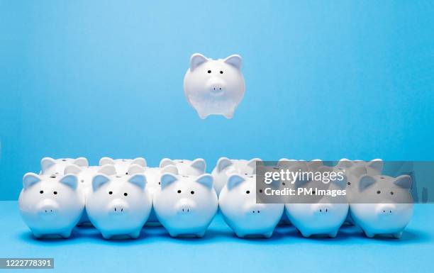 one piggy bank rising above the rest - personal appearance stock pictures, royalty-free photos & images