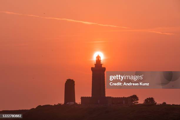 cap fréhel at sunrise with lighthouse directly in front of sun in brittany, france - cap fréhel stock pictures, royalty-free photos & images