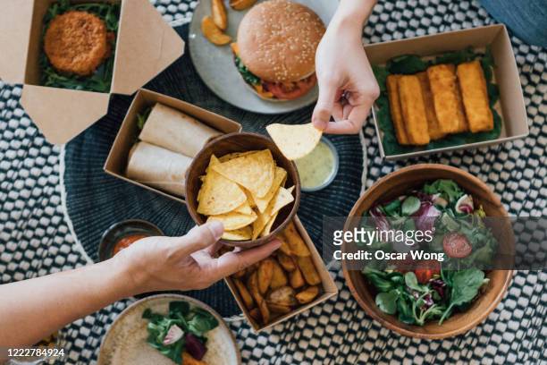 couple sharing takeaway food at home - american burger stock-fotos und bilder