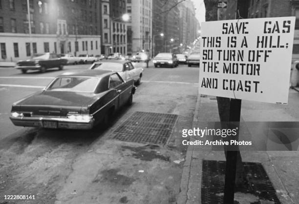 Sign by a road urging drivers to save fuel during the oil crisis of 1974-74 in the USA. The sign reads: 'save gas, This is a hill, so turn off the...