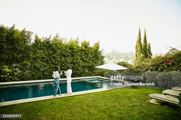 female friends hanging out by pool in backyard - friends poolside stock pictures, royalty-free photos & images
