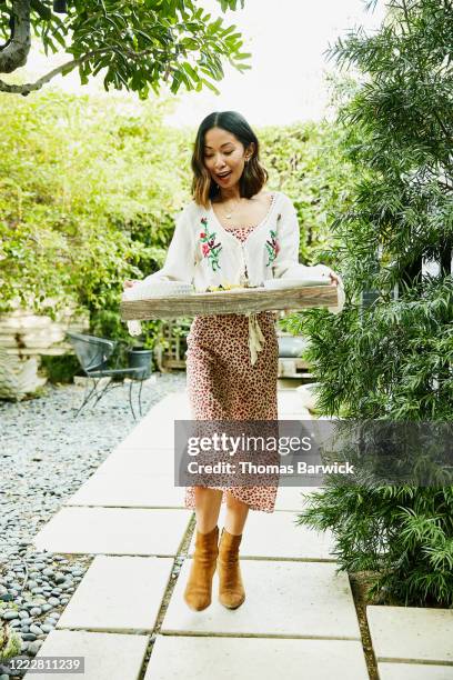 woman carrying tray of food to backyard for party - day california arrivals stockfoto's en -beelden