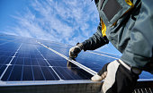 Male worker repairing photovoltaic solar panel.