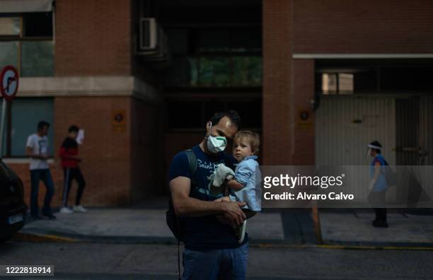 Man with his son walks down the street on May 4, 2020 in Huesca, Spain. Spain is opening new businesses as hairdressers, delivery food restaurants...