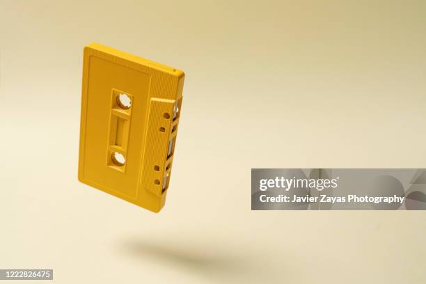 cassette tape floating on yellow background - radio art stock pictures, royalty-free photos & images