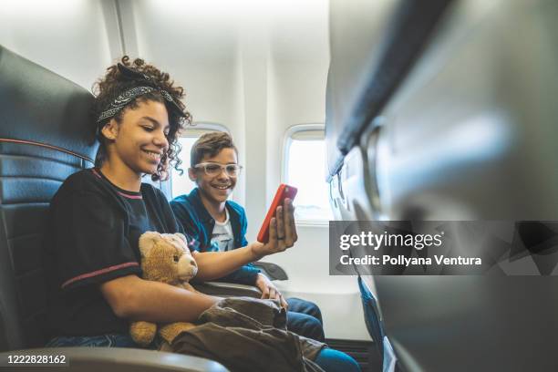 siblings watching video during flight - airport sitting family stock pictures, royalty-free photos & images