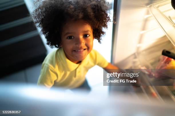 ritratto del bambino carino che apre il frigorifero a casa - funny fridge foto e immagini stock