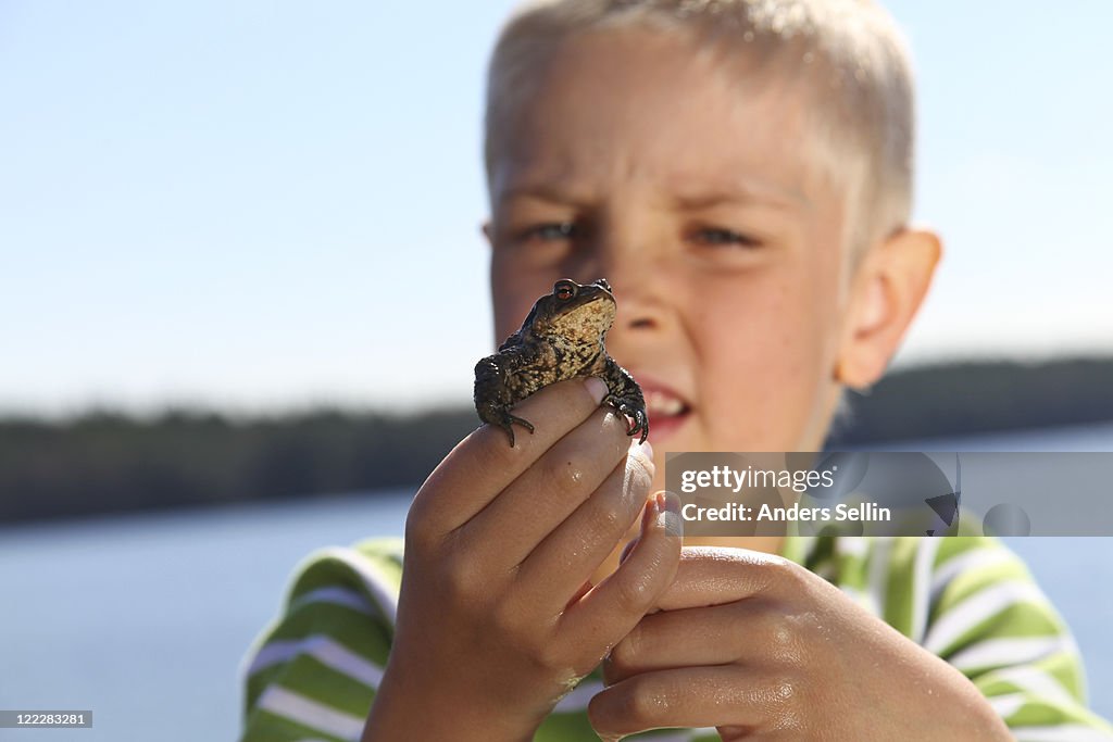 Young boy holding frog in front of his race