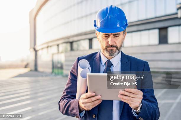 ausgereifter ingenieur mit seinem digitalen tablet auf einer baustelle. - real estate developer stock-fotos und bilder