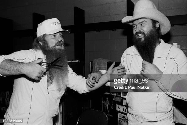 American Rock musician Dusty Hill as he pretends to cut the beard of his bandmate, Billy Gibbons, both are from the rock group ZZ Top, as they stand...