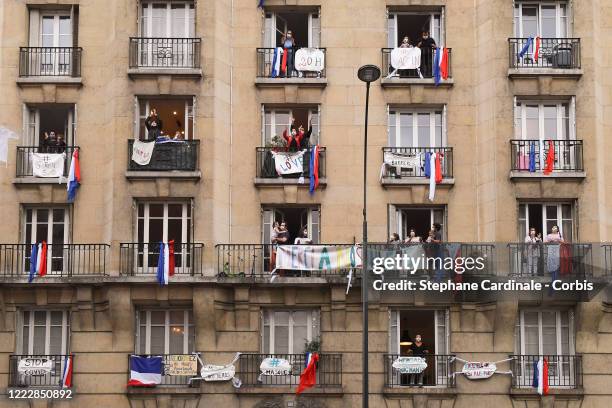 Inhabitants wearing protective masks applaud at 20:00 from their balcony decorated with French flags and messages to show their support to caregivers...