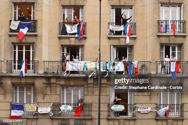 Inhabitants wearing protective masks applaud at 20:00 from their balcony decorated with French flags and messages to show their support to caregivers...