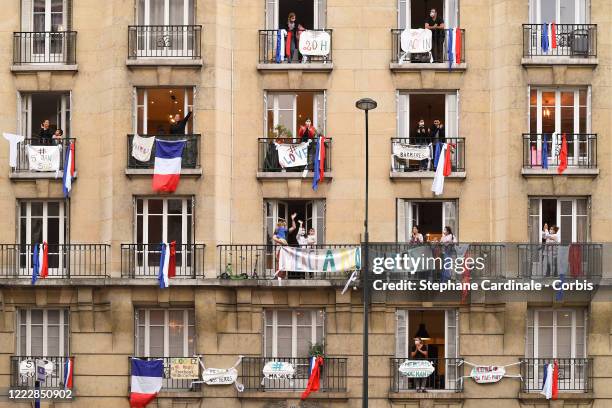 Inhabitants wearing protective masks applaud at 20:00 from their balcony decorated with French flags and messages to show their support to caregivers...