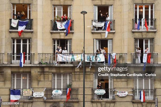 Inhabitants wearing protective masks applaud at 20:00 from their balcony decorated with French flags and messages to show their support to caregivers...